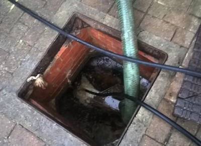 Jetting hose clearing a blocked drain chamber