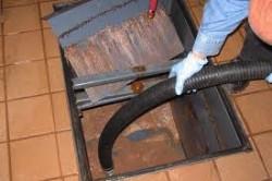 Grease trap being emptied in a commercial kitchen floor