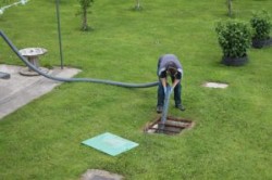 Operative de-sludging a tank in a garden